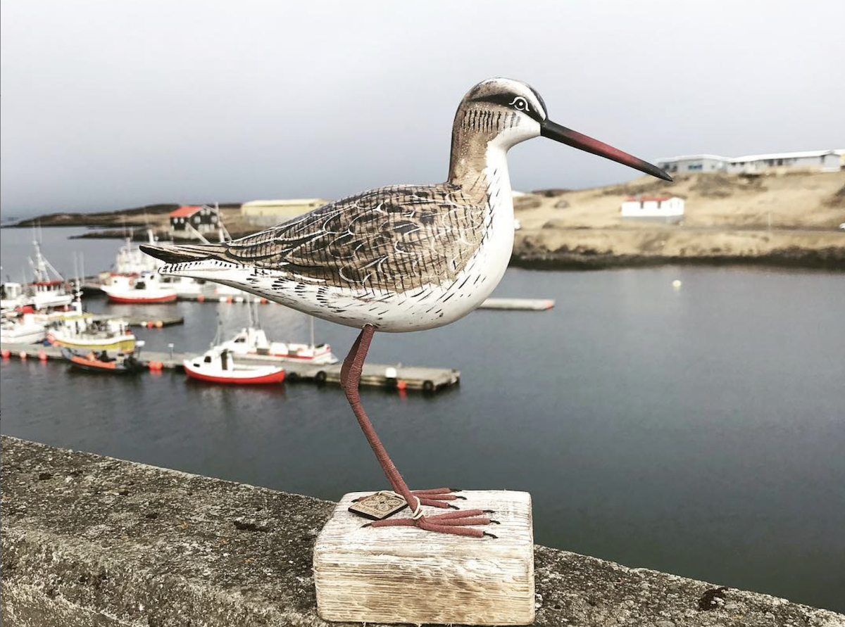 Handcrafted wooden shorebird sculpture at Bakkabúð Design Store in Djúpivogur harbor, Iceland.