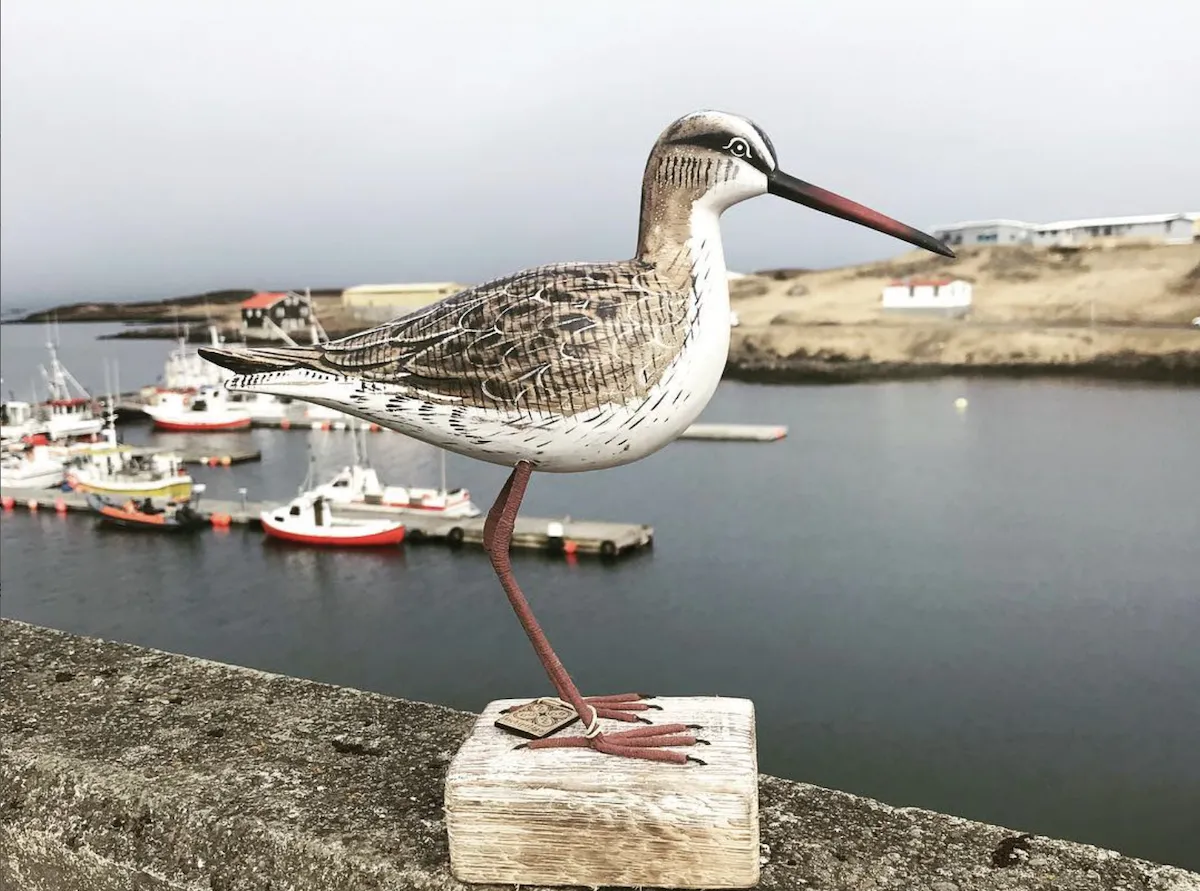 Handcrafted wooden shorebird sculpture at Bakkabúð Design Store in Djúpivogur harbor, Iceland.