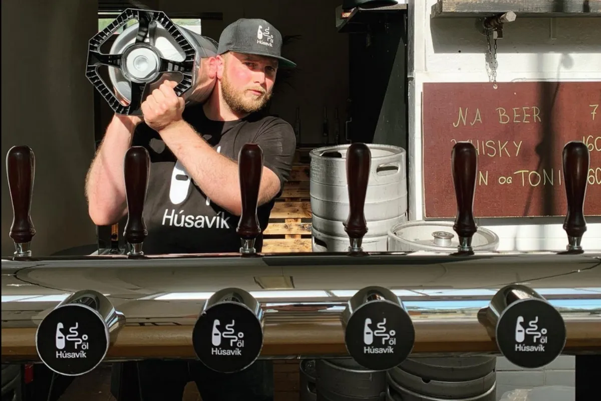 Man carrying keg behind beer taps at Húsavík öl.