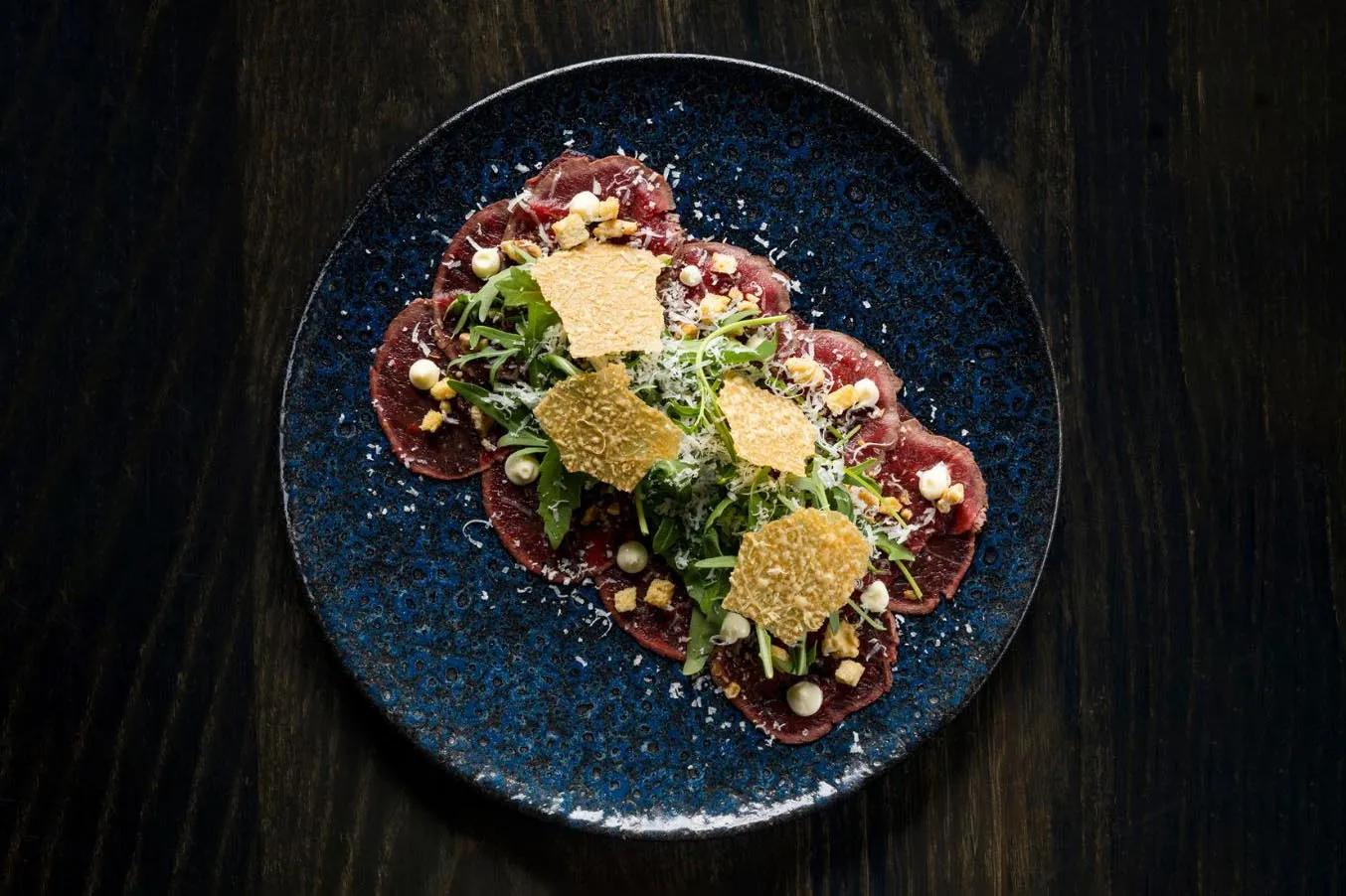 Beef carpaccio with arugula, parmesan, and crispy crackers at Sjávargrillið Seafood Grill Reykjavik.