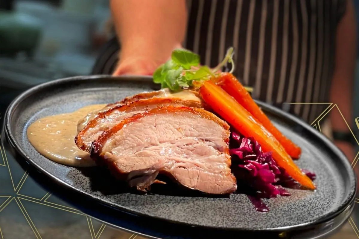 Gourmet plated pork belly with glazed carrots and red cabbage at Brasserie Kársnes in Reykjavik.