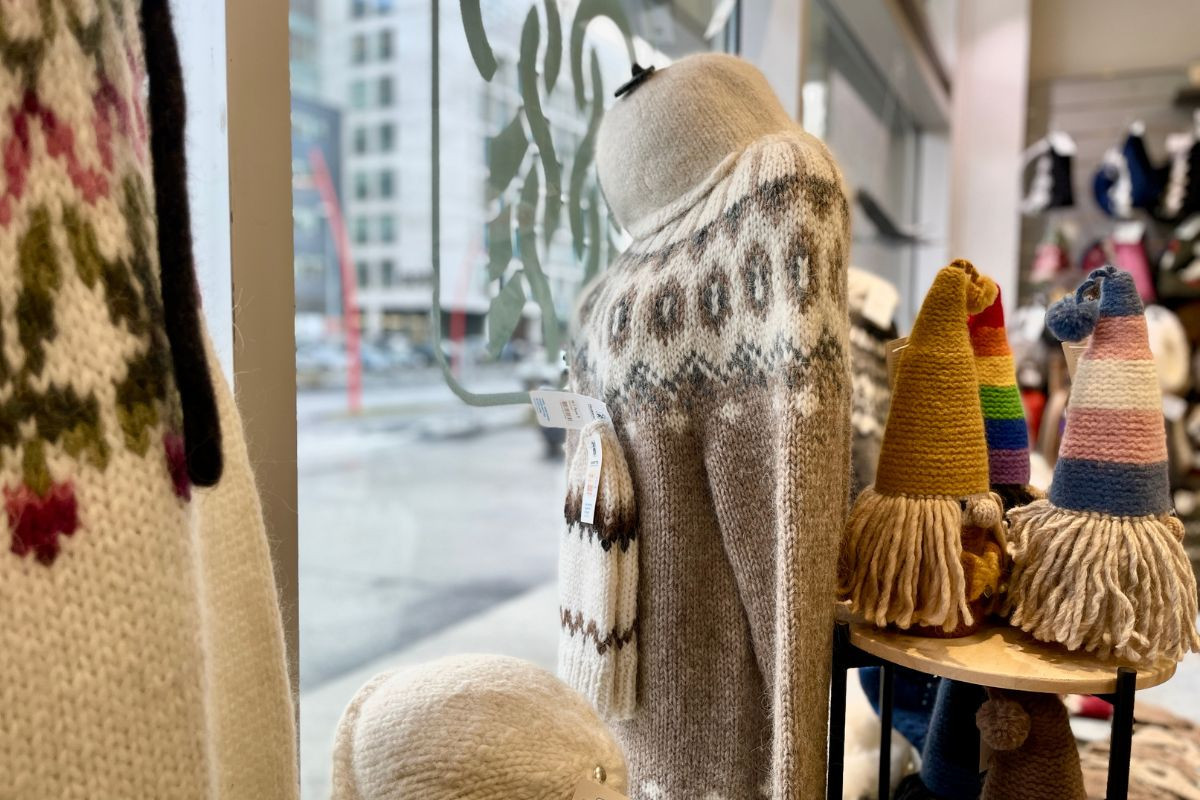 A window display of hand-knitted Icelandic wool sweaters and colorful gnomes at The Handknitting Association of Iceland, Reykjavik, recommended by Handpicked Iceland.