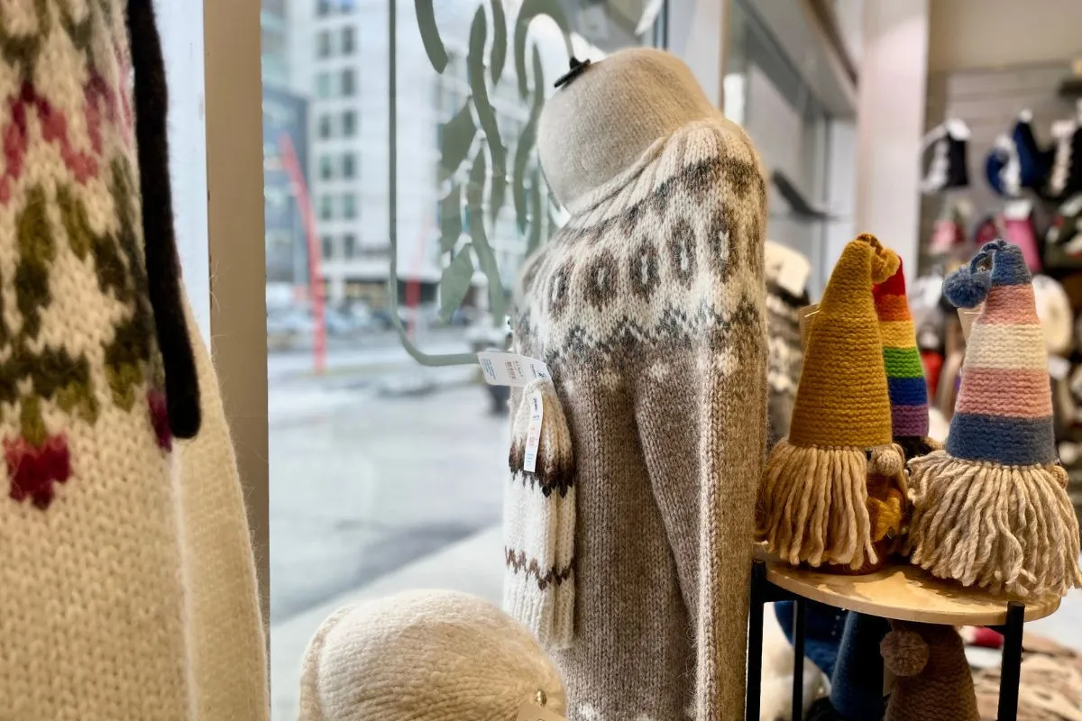 A window display of hand-knitted Icelandic wool sweaters and colorful gnomes at The Handknitting Association of Iceland, Reykjavik, recommended by Handpicked Iceland.
