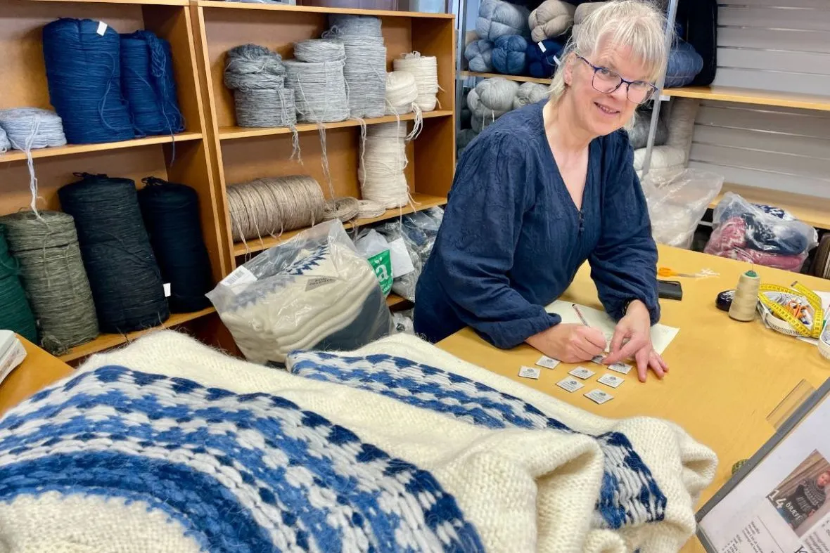 Labeling a traditional blue and white lopapeysa at The Handknitting Association of Iceland in Reykjavik.