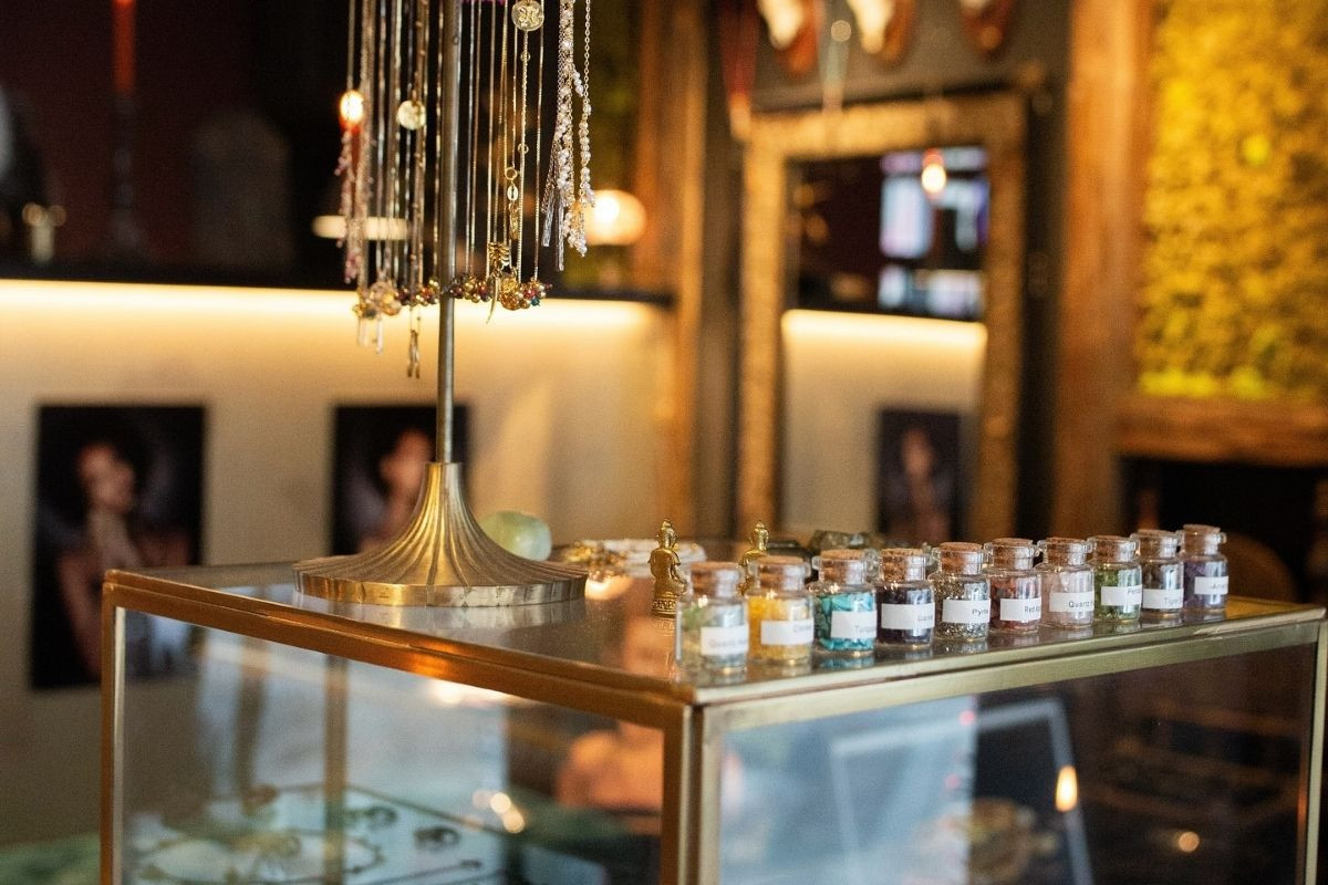Glass display case at Hildur Hafstein Jewelry with apothecary jars of colorful raw gemstones and crystals.