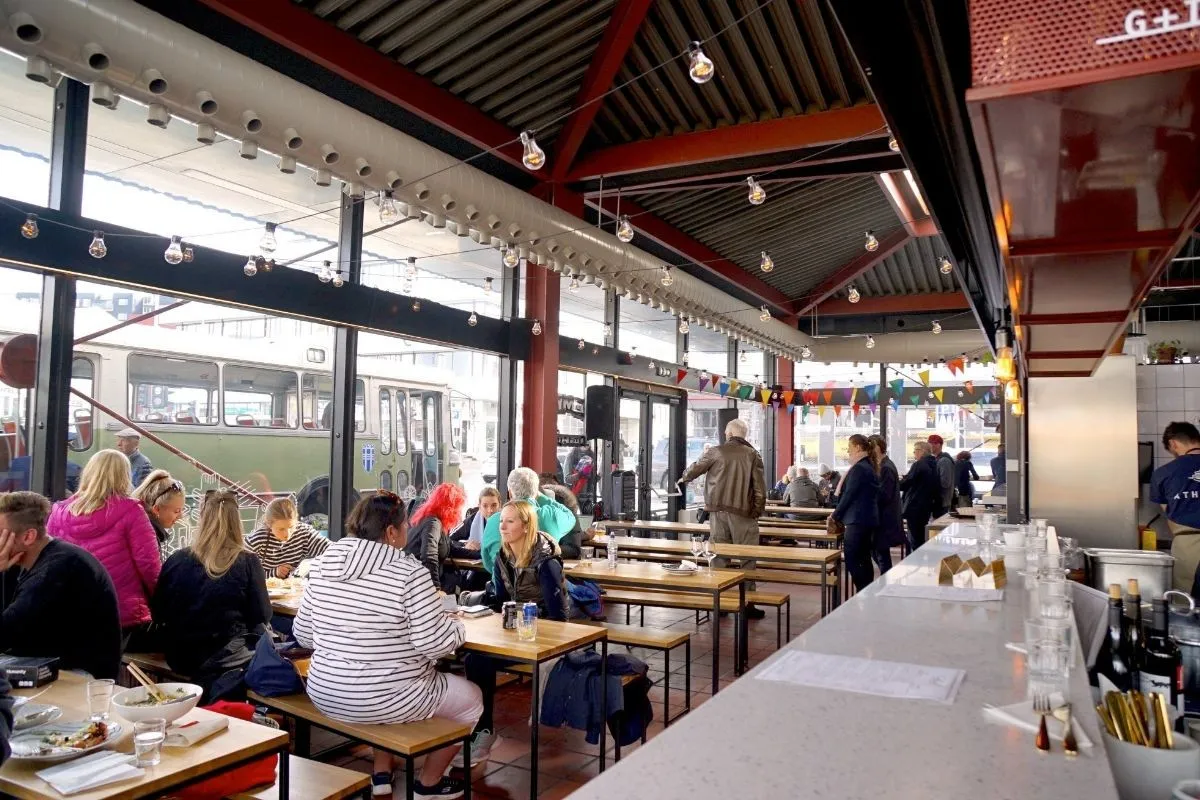 People enjoying meals at communal seating in Hlemmur Foodhall in Reykjavik, recommended by Handpicked Iceland.