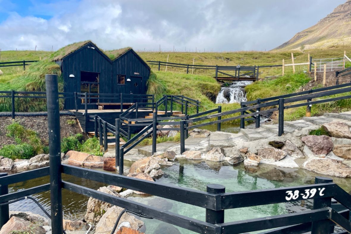 Hraunsnef nature baths with turf-roofed buildings and a small waterfall in West Iceland.