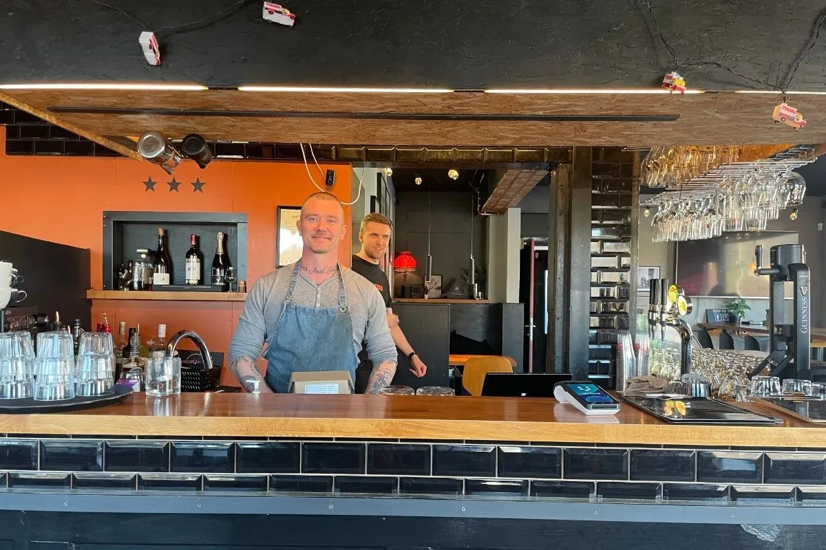 Friendly staff member at the Mossley Street Food service counter in Kópavogur.