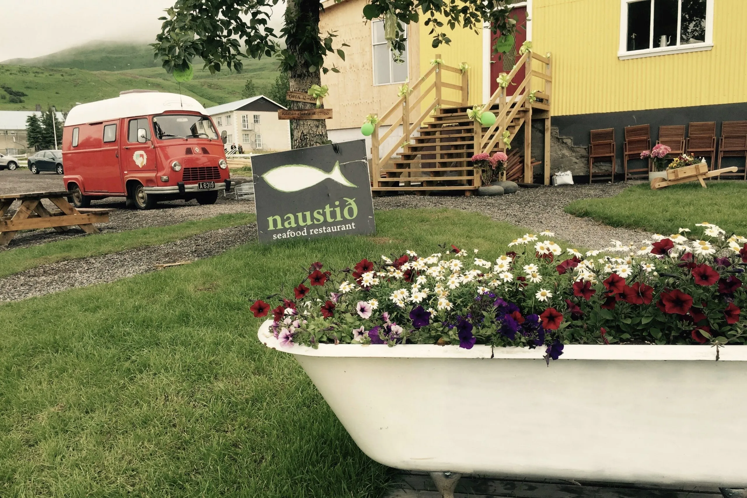 Grassy outdoor area at Naustið Seafood Restaurant in Húsavík featuring the Handpicked van.