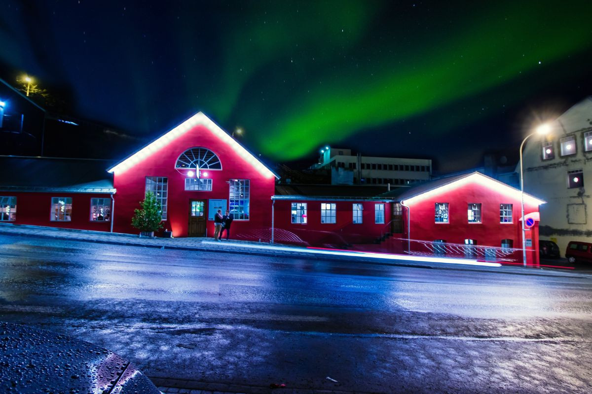 The red exterior of Rub23 restaurant in Akureyri under the northern lights.