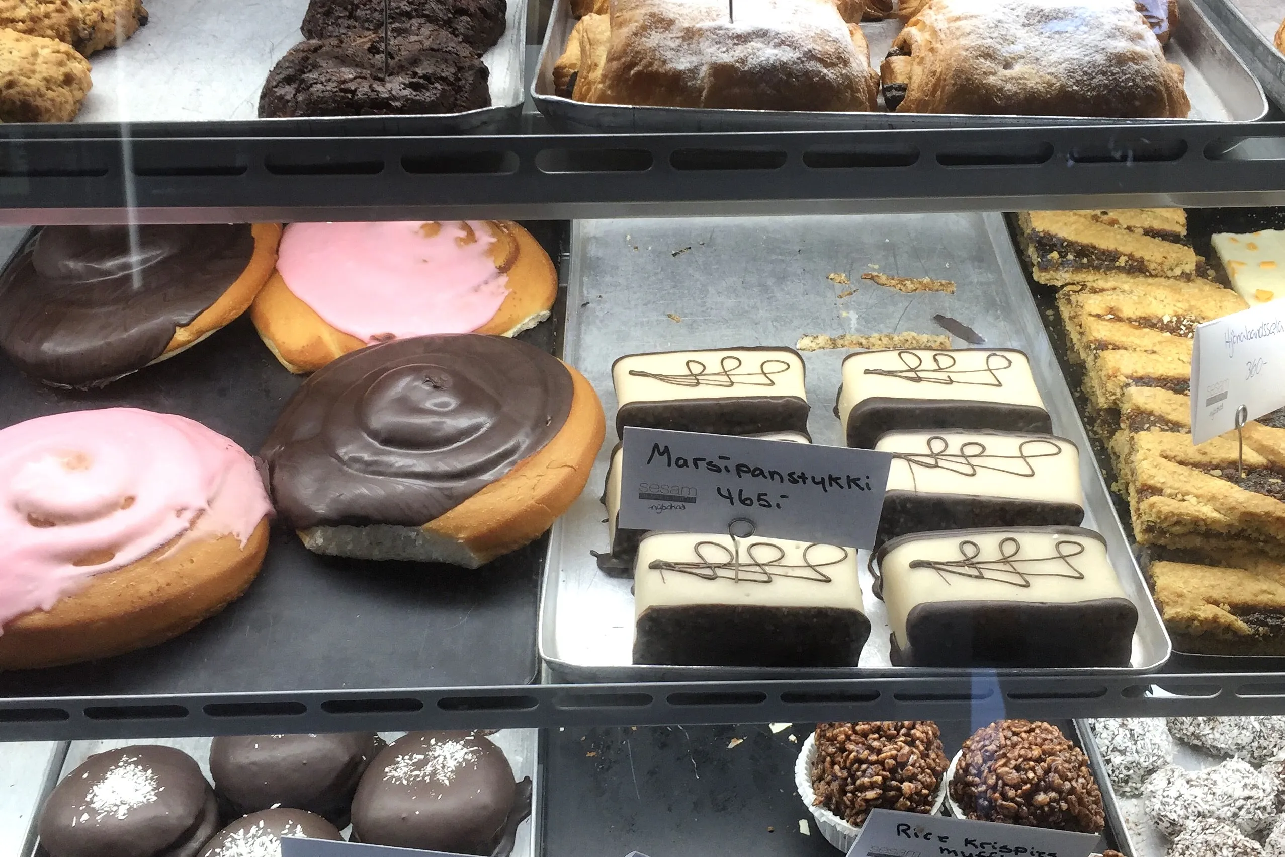 Assorted Icelandic pastries at Sesam Brauðhús in Reyðarfjörður, including glazed rolls, marzipan bars, and chocolate cakes.