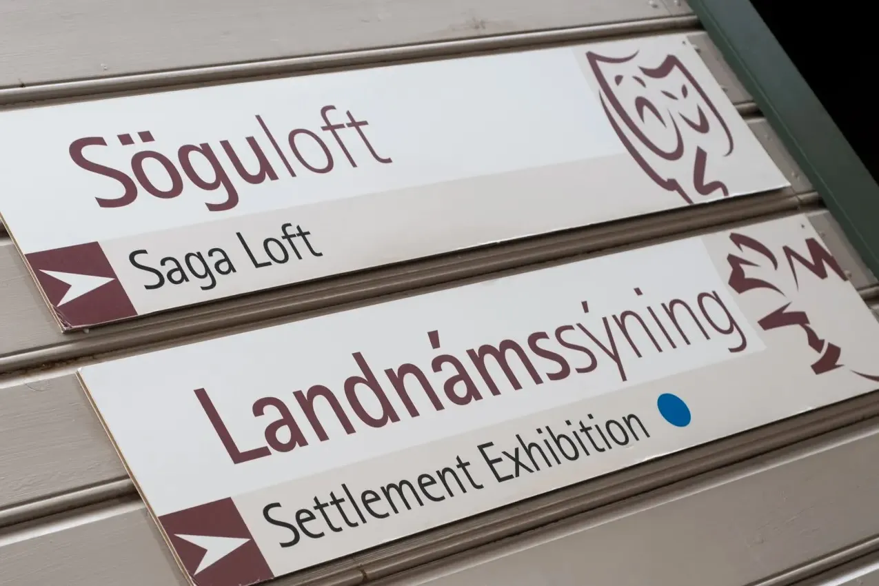 Interior signage at The Settlement Center pointing toward the Saga Loft and the Settlement Exhibition.