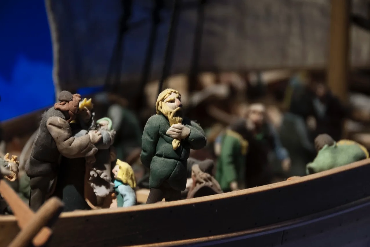 Hand-carved wooden figures of Viking settlers on a ship at The Settlement Center museum.