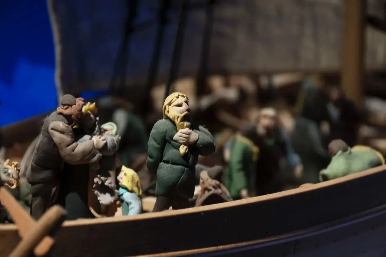 Hand-carved wooden figures of Viking settlers on a ship at The Settlement Center museum.