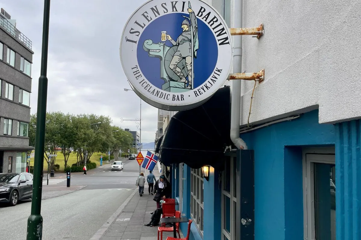 The exterior of The Icelandic Bar (Íslenski barinn) featuring its iconic blue and white round sign in downtown Reykjavik.
