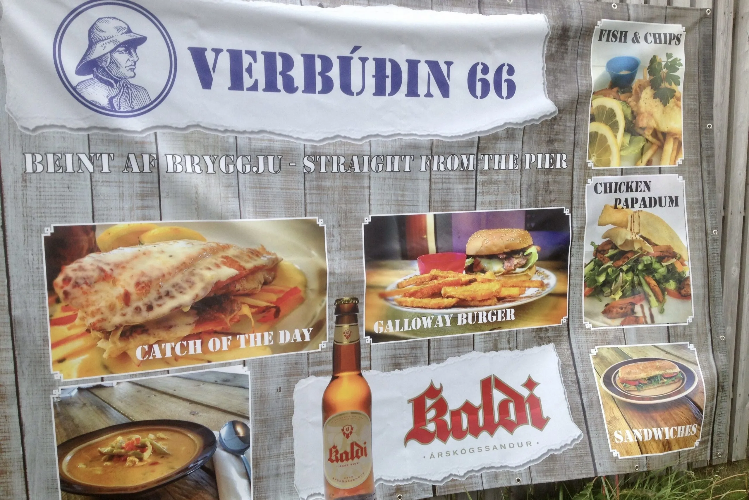 Outdoor restaurant sign displaying menu items and Kaldi beer at Verbúðin 66 in Hrisey.