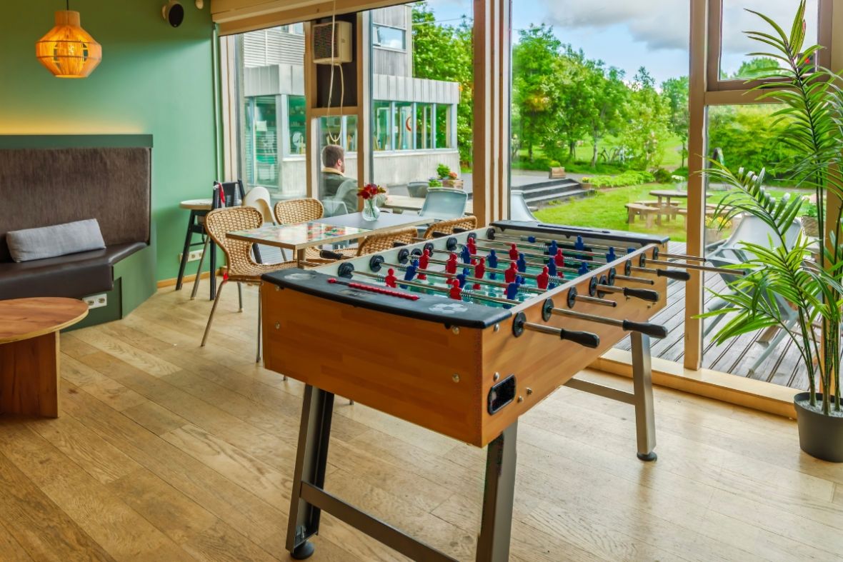 Foosball table and seating area with large windows at Dalur Cafe in Reykjavik.