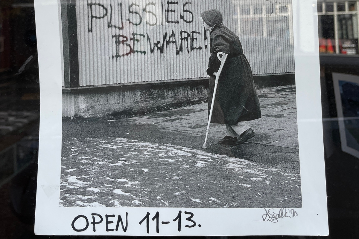 Photography print of an elderly person walking past graffiti at Fótógrafí