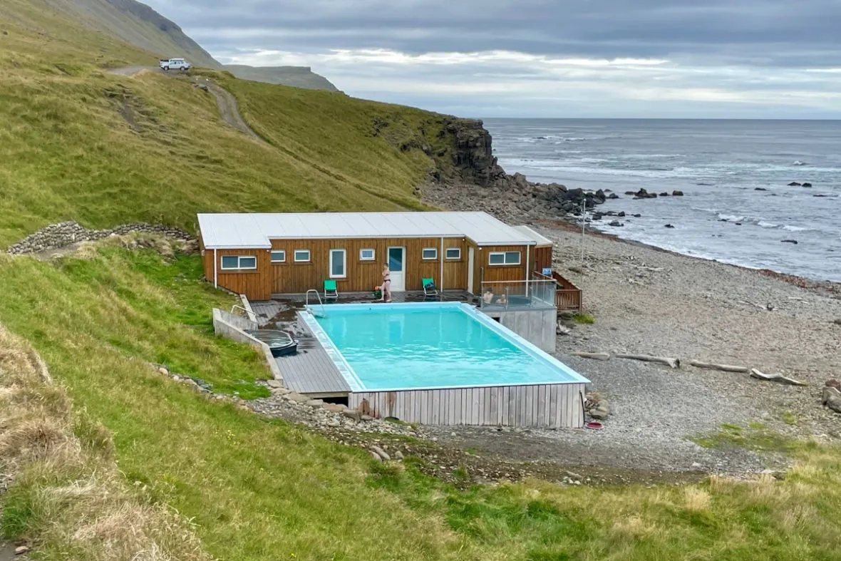 Krossneslaug geothermal pool beside a pebble beach in the Westfjords, recommended by Handpicked Iceland.