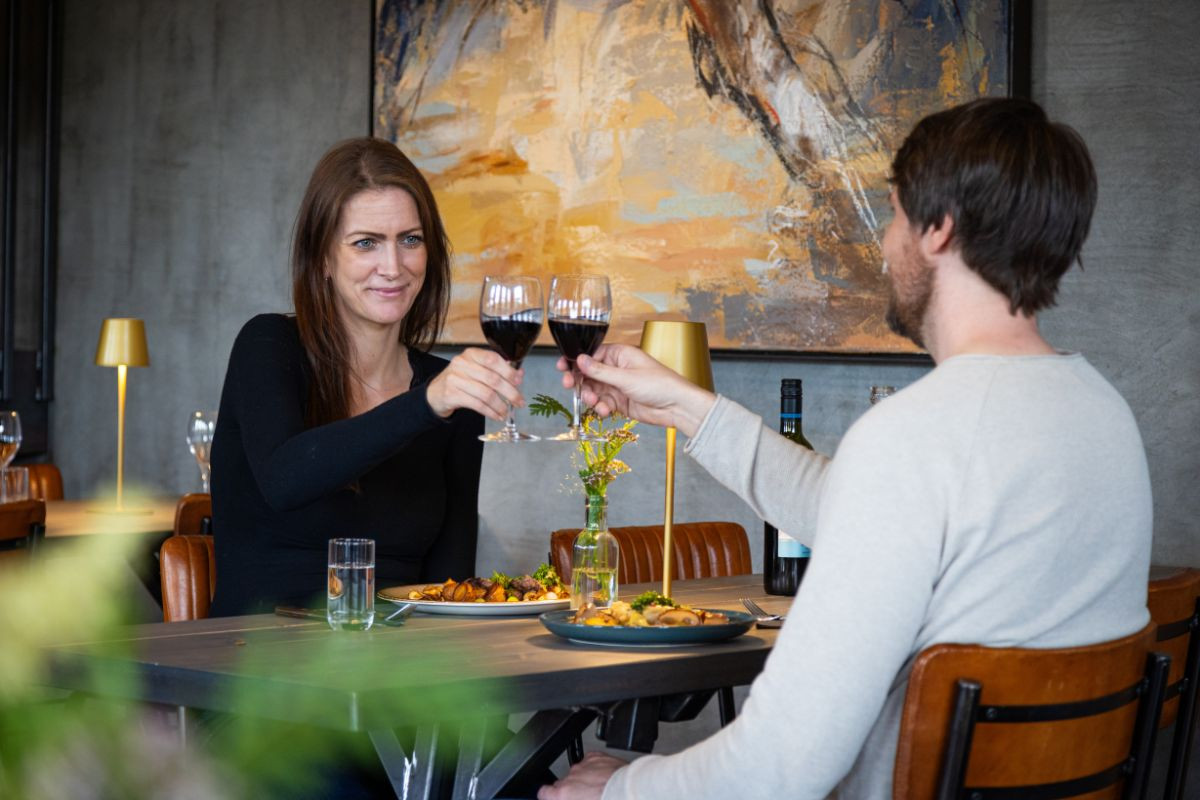 Couple enjoying dinner and wine at Hlaðan Restaurant.