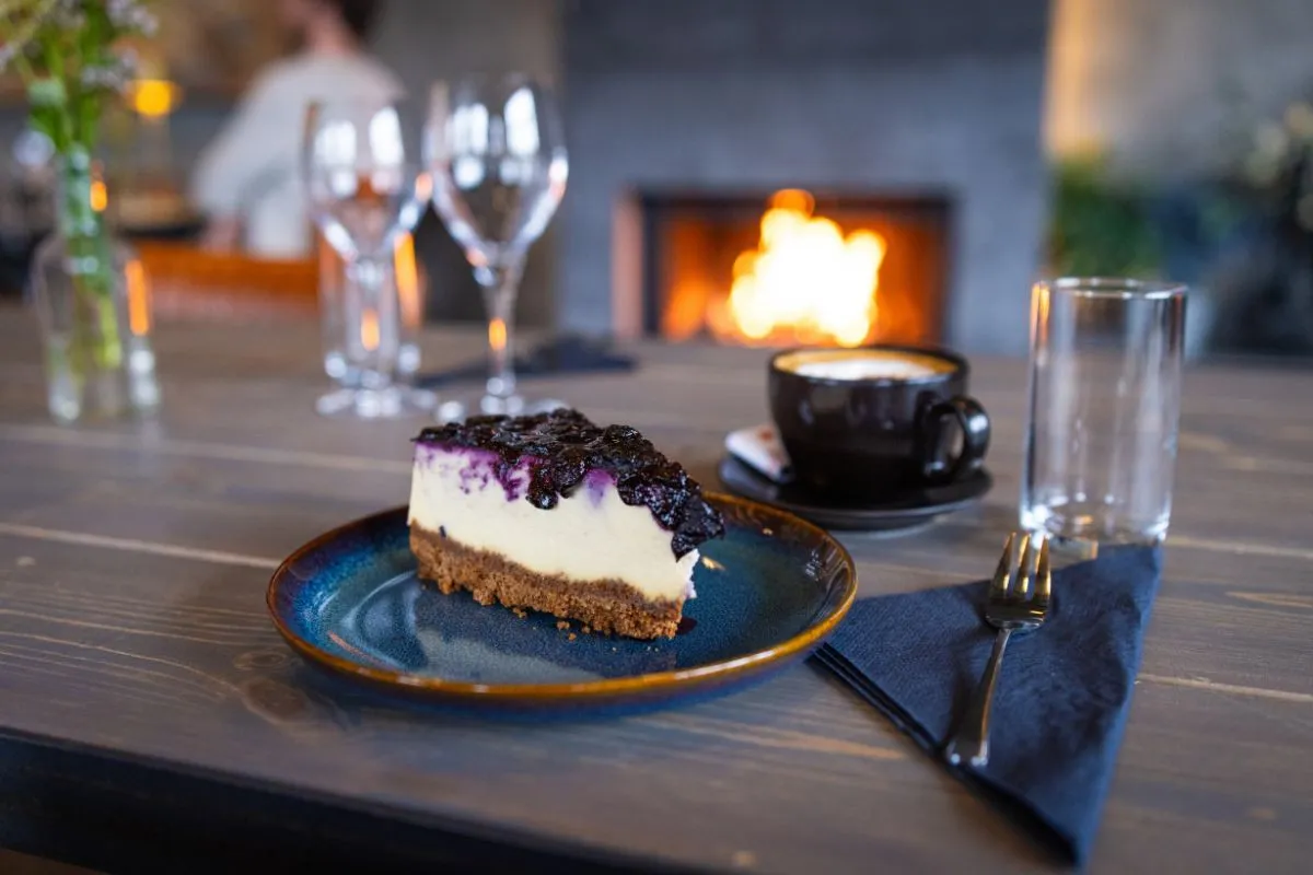 Blueberry cheesecake and coffee by the fireplace at Hlaðan Restaurant.
