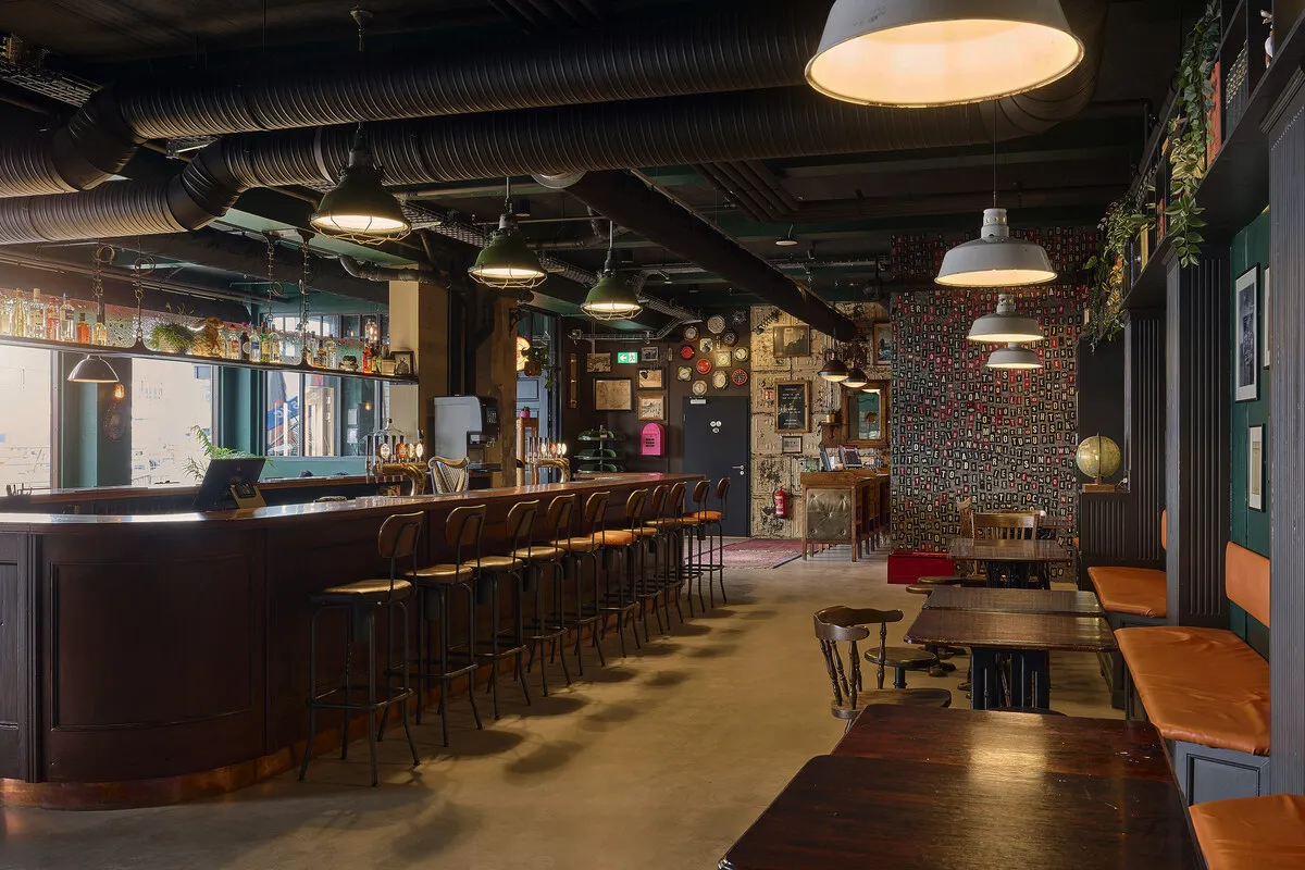 KEX Bar lounge in Reykjavík with a long wooden bar, stools and pendant lights, recommended by Handpicked Iceland