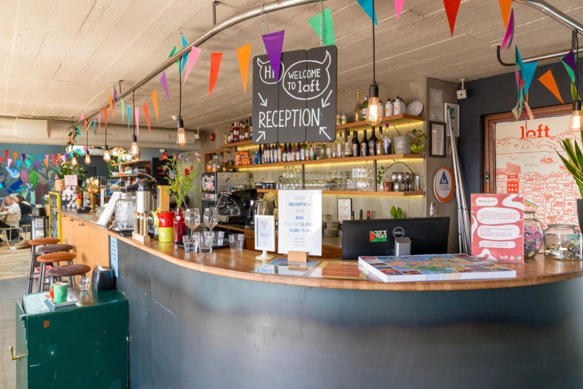 Loft Hostel Bar reception and drink counter with colorful bunting in Reykjavik.
