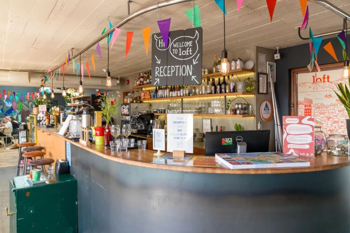 Loft Hostel Bar reception and drink counter with colorful bunting in Reykjavik.