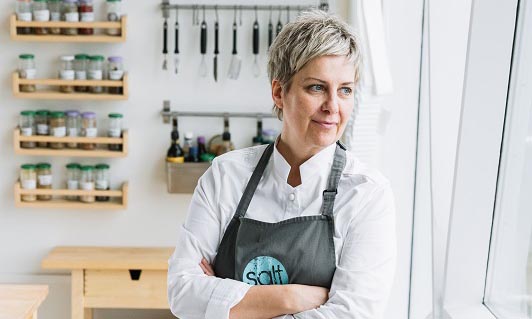 Professional chef wearing a Salt Eldhús apron in their bright kitchen studio in Reykjavik.