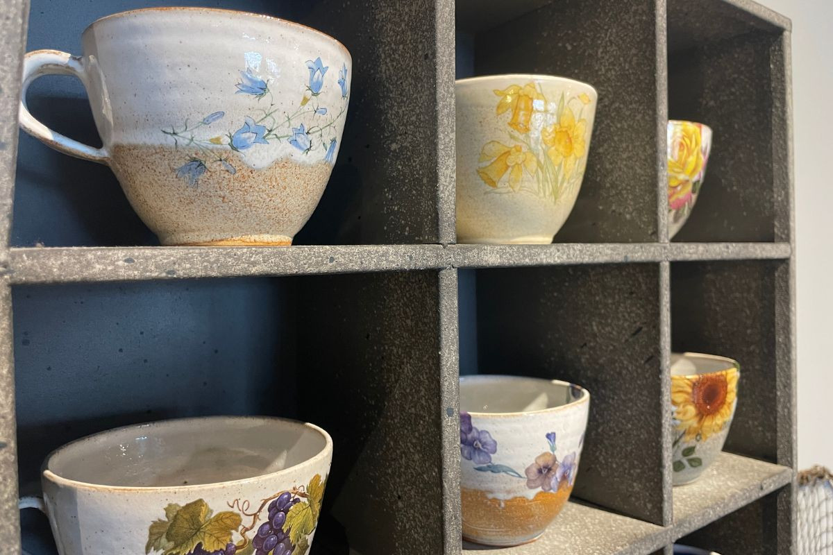 Hand-painted floral ceramic mugs on display at Blóðberg shop in Akureyri.
