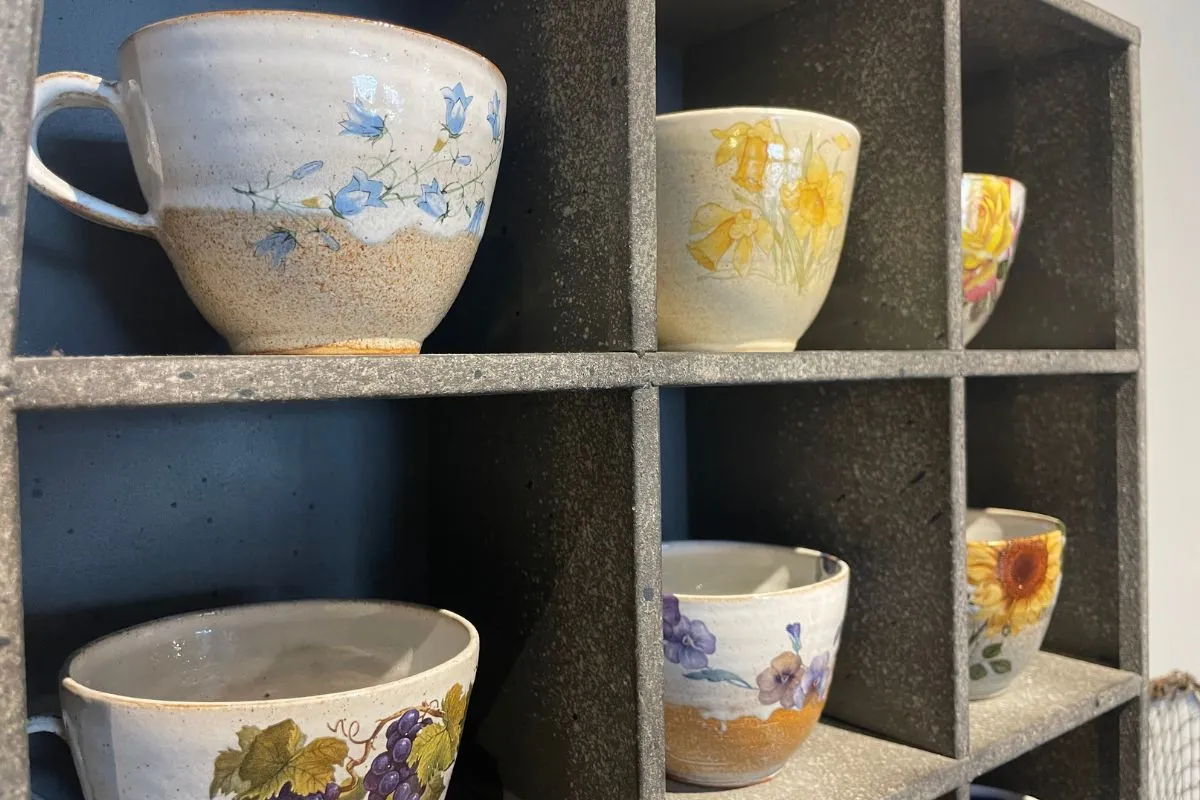 Hand-painted floral ceramic mugs on display at Blóðberg shop in Akureyri.