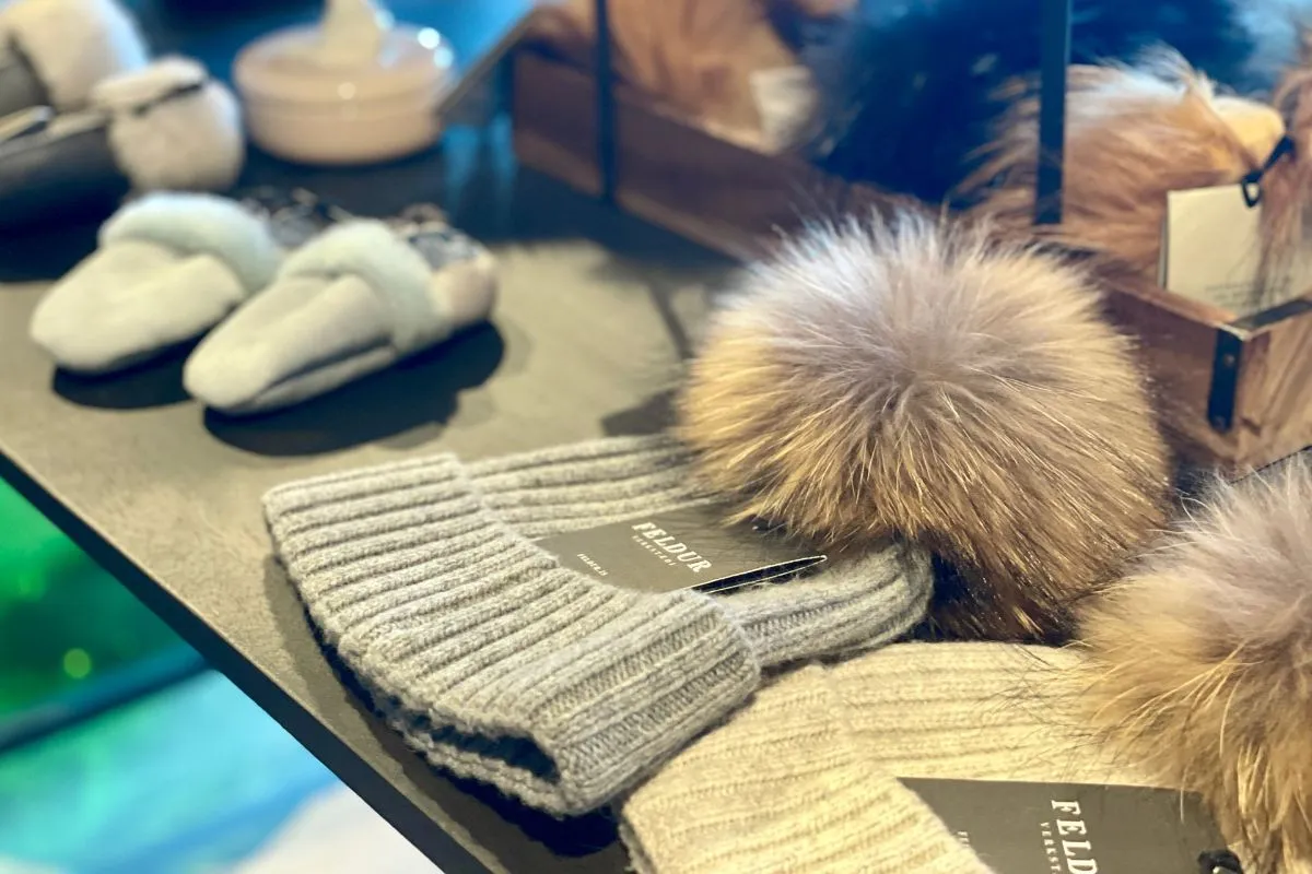Feldur Verkstæði wool beanies and slippers with faux fur pom-poms at Blóðberg shop in Akureyri.