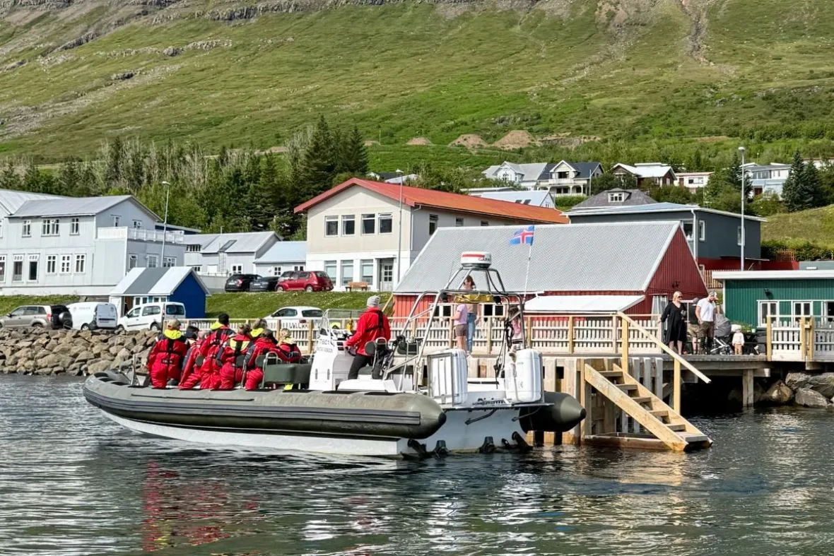 Fjarðaferðir boat tour meeting point at the Neskaupstaður waterfront with Icelandic houses in the background.