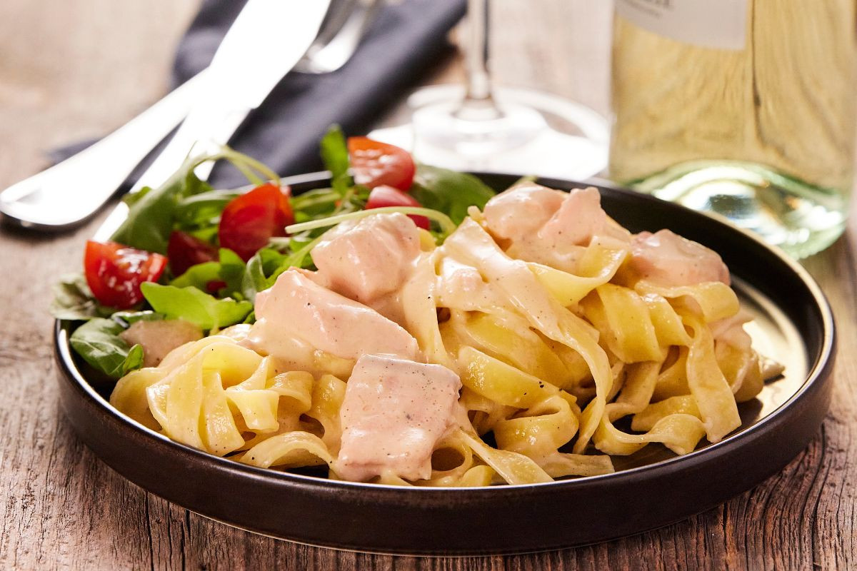 Creamy salmon pasta with fresh tomato salad at Midgard Restaurant in Hvolsvöllur.