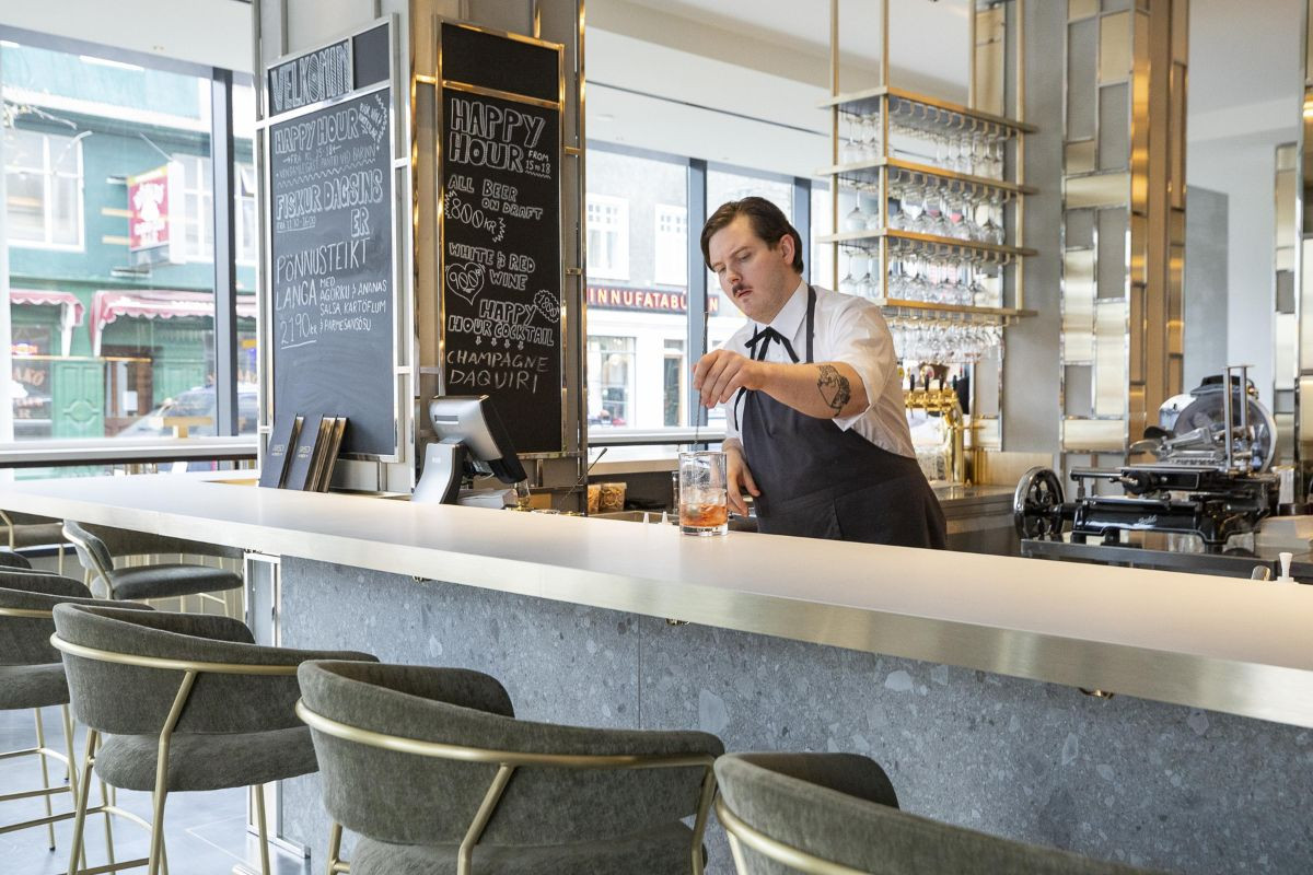 A bartender at the modern bar counter inside Eiriksson Brasserie in Reykjavik, recommended by Handpicked Iceland.