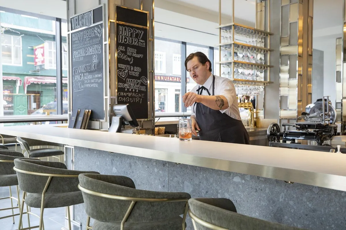 A bartender at the modern bar counter inside Eiriksson Brasserie in Reykjavik, recommended by Handpicked Iceland.