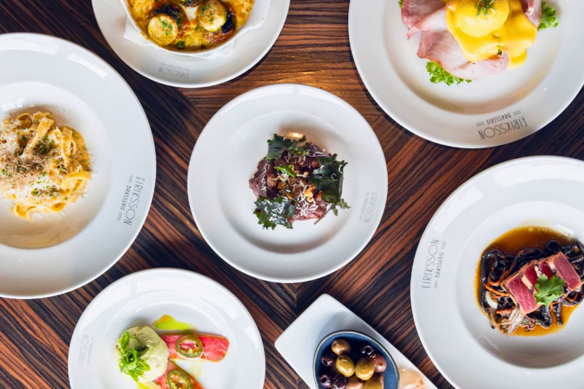 An overhead flat lay of gourmet Italian-influenced dishes, including pasta, seafood, and appetizers at Eiriksson Brasserie in Reykjavik.