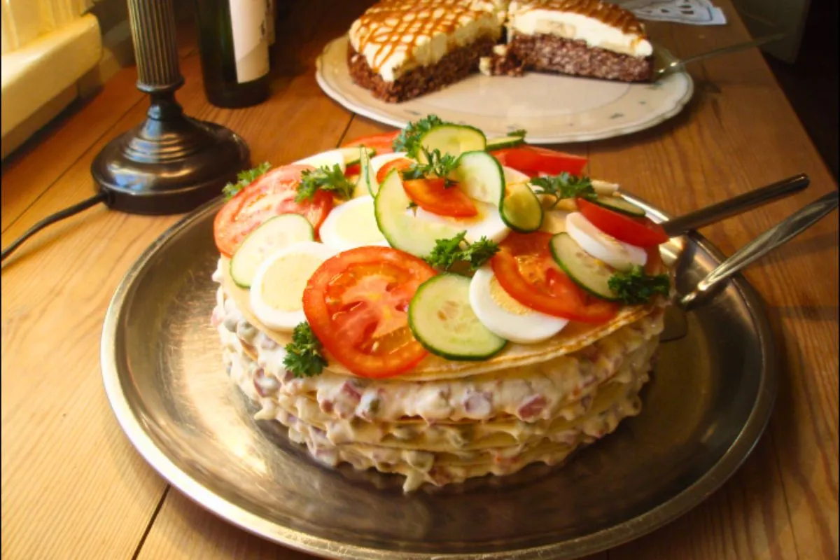 A savory Icelandic layer cake topped with sliced eggs, tomatoes, and cucumbers at Áskaffi – Food tour Héðinsminni.