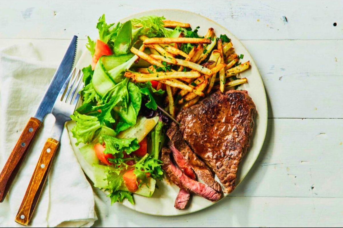 Sliced steak served with french fries and a side salad at French Touch Bistro.
