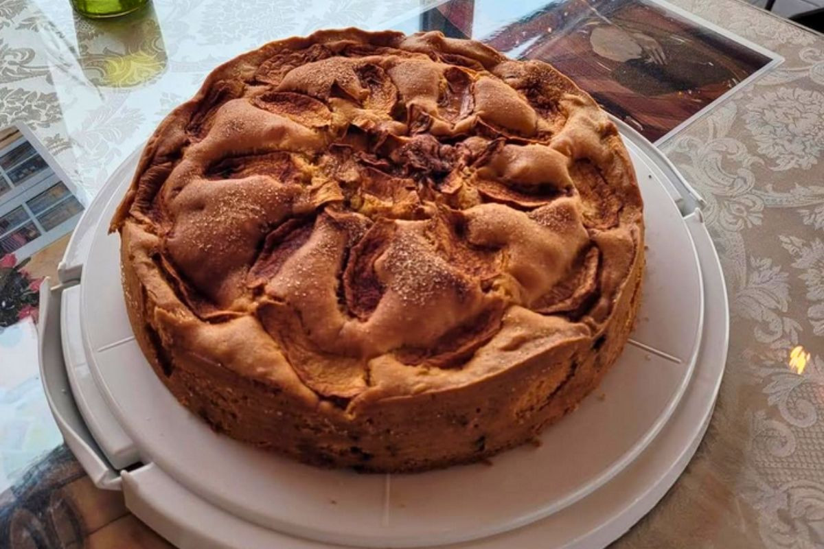 A freshly baked golden apple cake served on a white platter at Hjá góðu fólki café.
