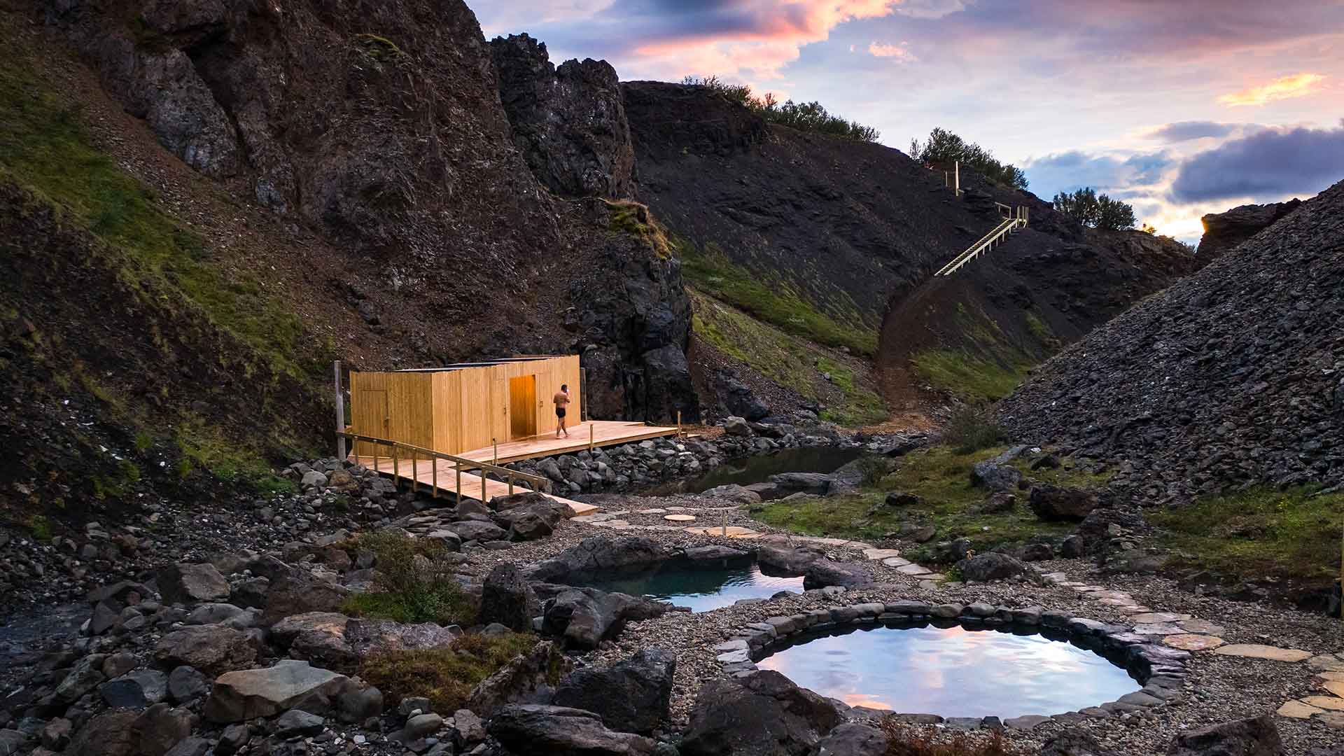 Scenic twilight view of the natural hot tubs at Húsafell Canyon Baths surrounded by rocky cliffs in West Iceland.