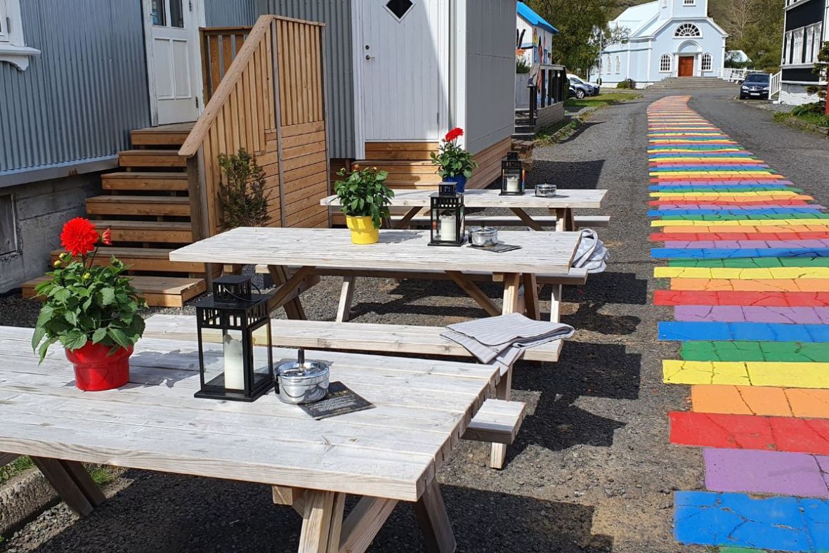 Patio seating area at Kaffi Lára El Grillo Bar in Iceland featuring wooden tables decorated with flowers and lanterns.