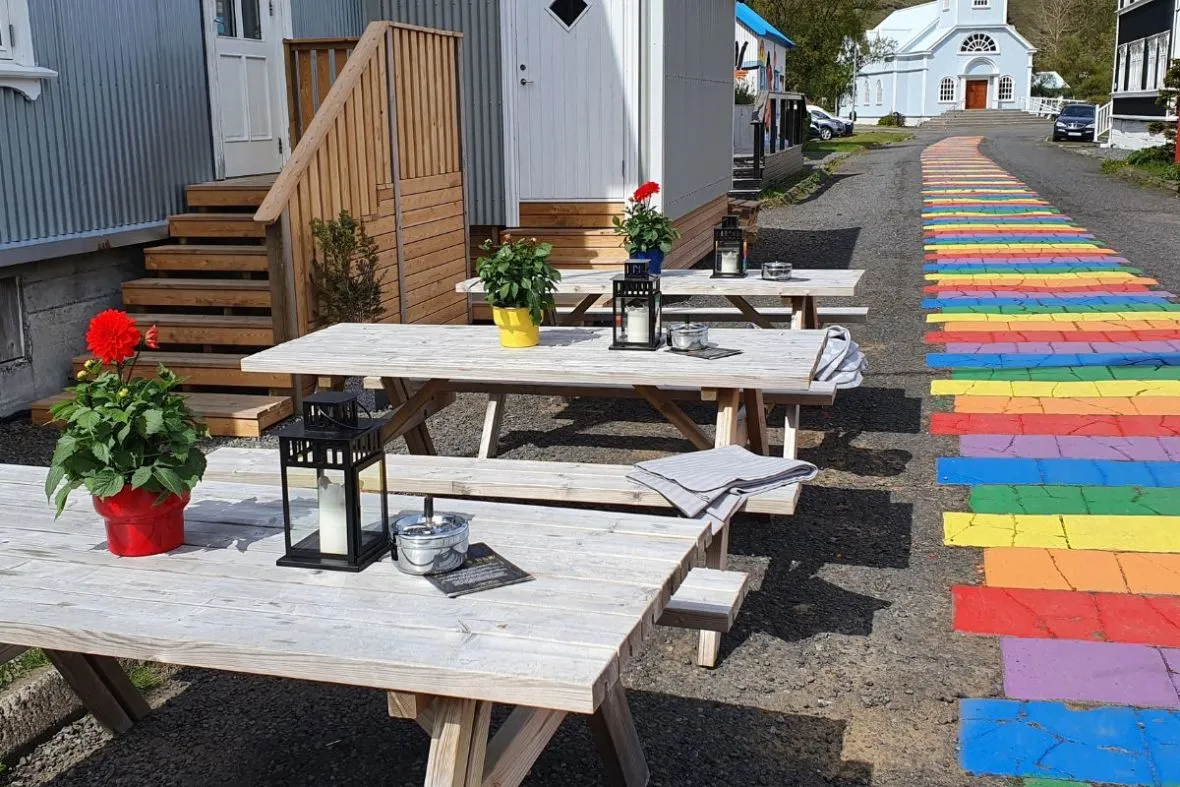 Patio seating area at Kaffi Lára El Grillo Bar in Iceland featuring wooden tables decorated with flowers and lanterns.
