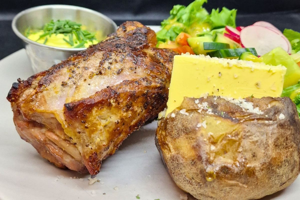 Roasted meat dish with baked potato and fresh salad served at Kaffi Lára El Grillo Bar.