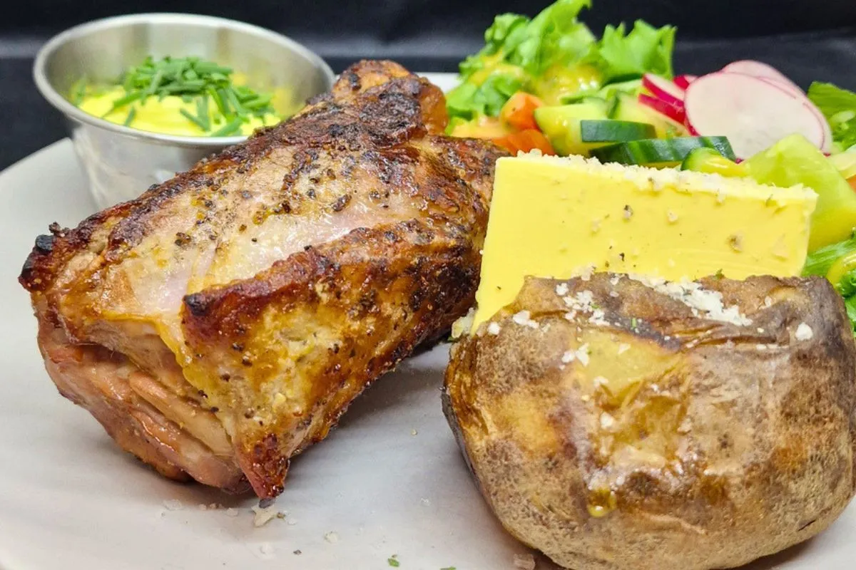 Roasted meat dish with baked potato and fresh salad served at Kaffi Lára El Grillo Bar.