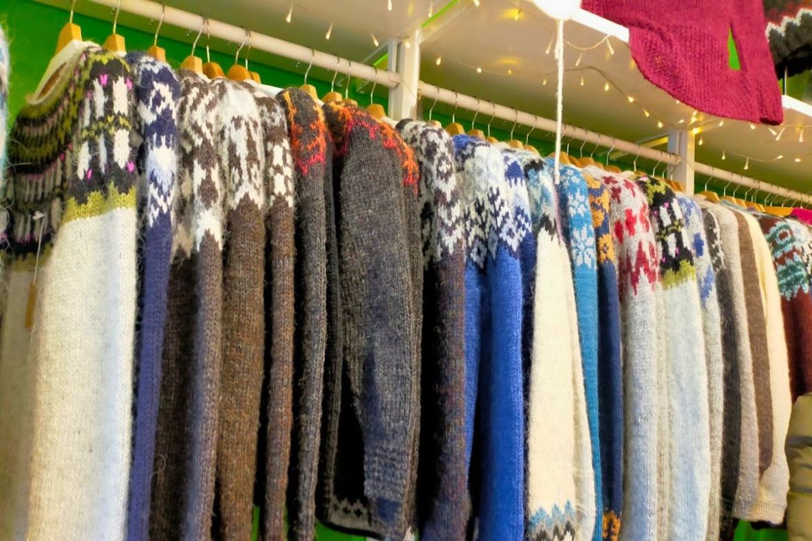 Traditional Icelandic wool sweaters hanging on a display rack at Ljómalind Local Market.