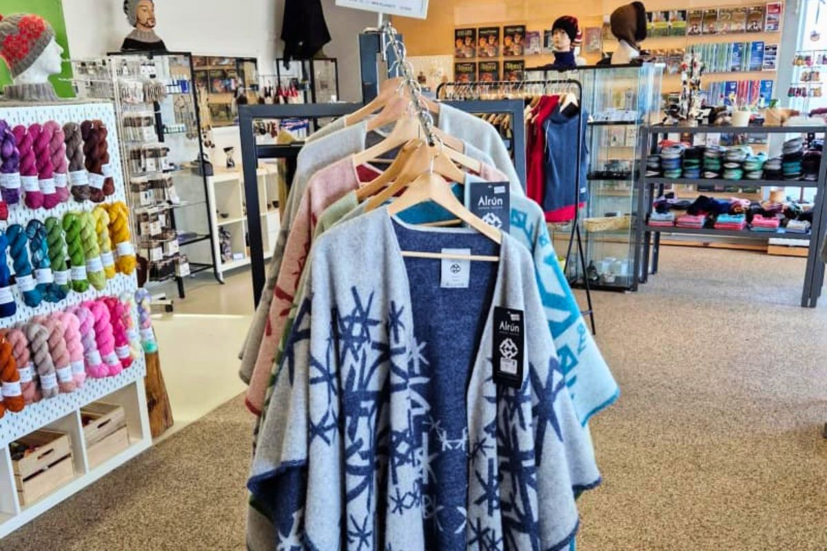 Patterned wool capes and ponchos displayed on clothing racks at Ljómalind Local Market.