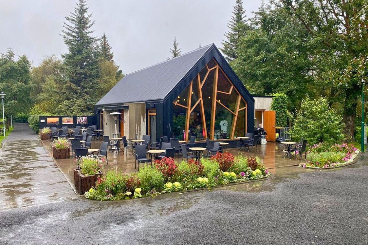 Exterior view of LYST café's architectural building and outdoor patio seating in Akureyri Botanical Garden.