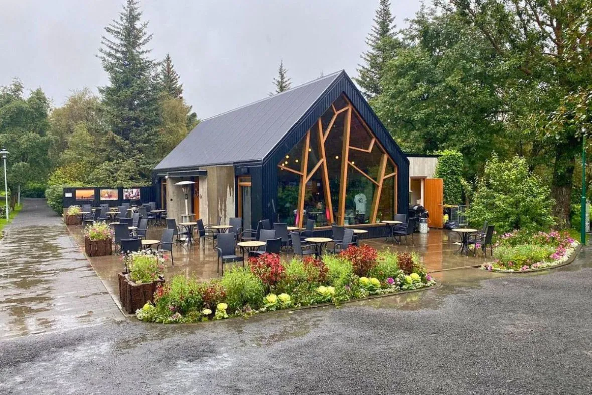 Exterior view of LYST café's architectural building and outdoor patio seating in Akureyri Botanical Garden.