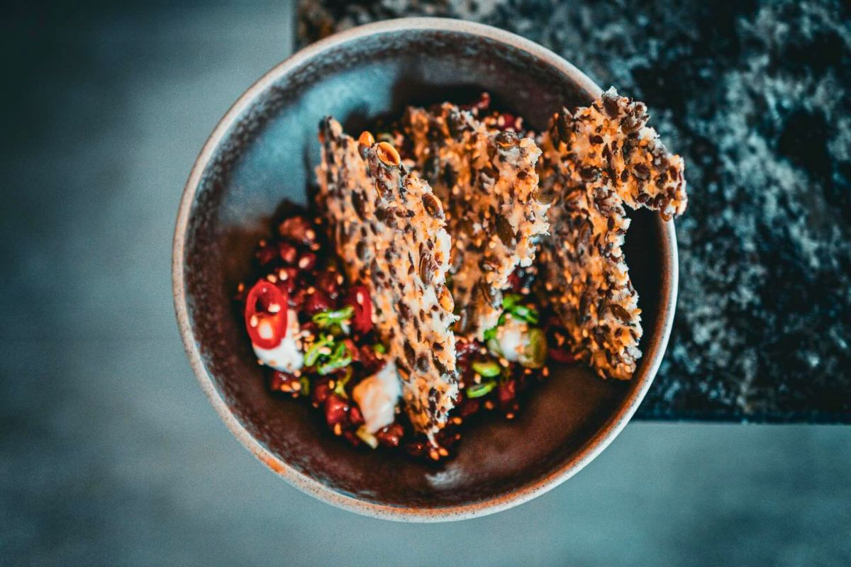 Gourmet appetizer bowl topped with crispy seed crackers at LYST Akureyri.